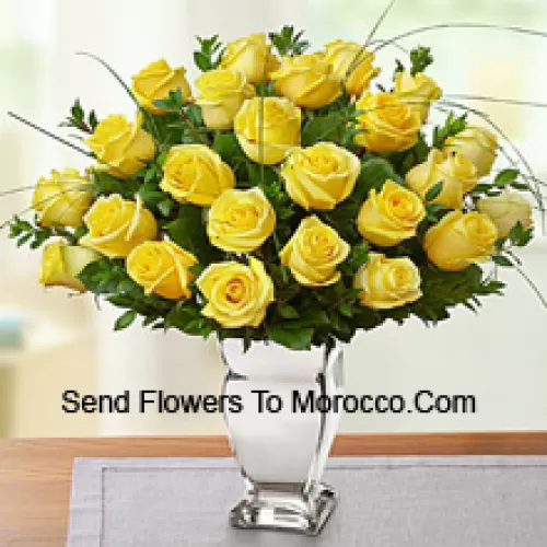 25 Yellow Roses With Some Ferns In A Glass Vase