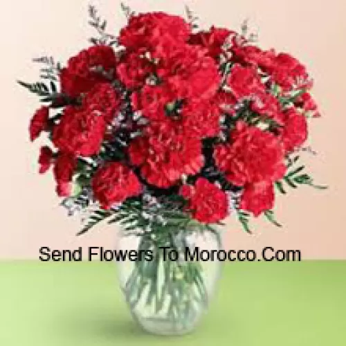 37 Red Carnations With Seasonal Fillers In A Glass Vase