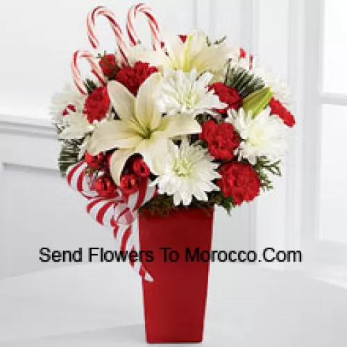 Bursts with the bright cheer and jubilant beauty of this special season. White Asiatic Lilies and chrysanthemums sit amongst red mini carnations, assorted holiday greens, red glass balls, three candy canes and festive ribbon, perfectly arranged in a red ceramic vase to create a lively bouquet of merry wishes for a splendid holiday season! (Please Note That We Reserve The Right To Substitute Any Product With A Suitable Product Of Equal Value In Case Of Non-Availability Of A Certain Product)