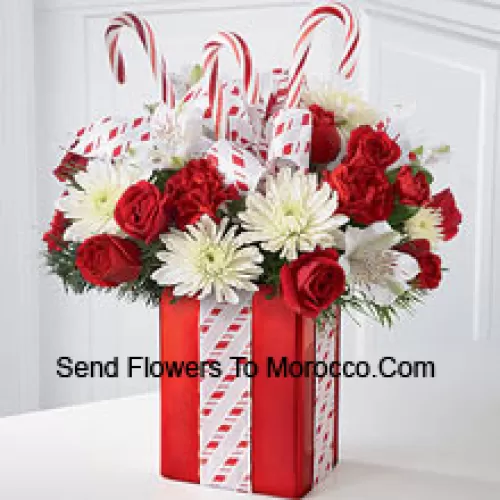 Ce bouquet les éblouira par sa joie fantasque et sa beauté pleine d'énergie ! Un magnifique arrangement de chrysanthèmes blancs, de œillets rouges et de roses spray est niché parmi des verdure de Noël dans un vase rouge brillant orné de cannes de bonbon et emballé à la perfection avec un joli nœud, lui donnant l'apparence du plus beau cadeau de Noël. (Veuillez noter que nous nous réservons le droit de substituer tout produit par un produit approprié de valeur égale en cas de non-disponibilité d'un certain produit)