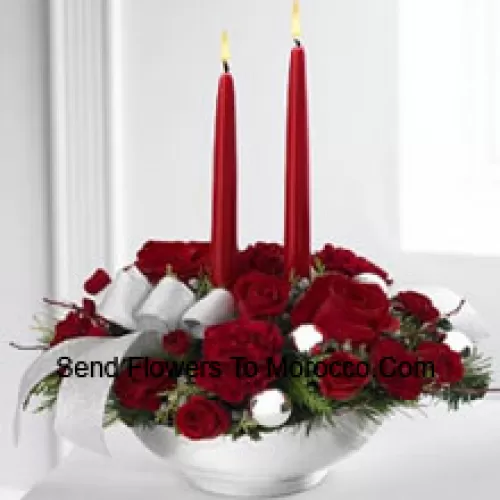 Our Holiday Elegance Centerpiece will add that special spark to their seasonal celebration with its vibrant array of crimson blooms! Red roses, carnations and spray roses sit amongst holiday greens in a posh ceramic silver container adorned with a beautiful silver ribbon accent and two taper candles to bring a holiday glow of warmth and peace to their table. (Please Note That We Reserve The Right To Substitute Any Product With A Suitable Product Of Equal Value In Case Of Non-Availability Of A Certain Product)